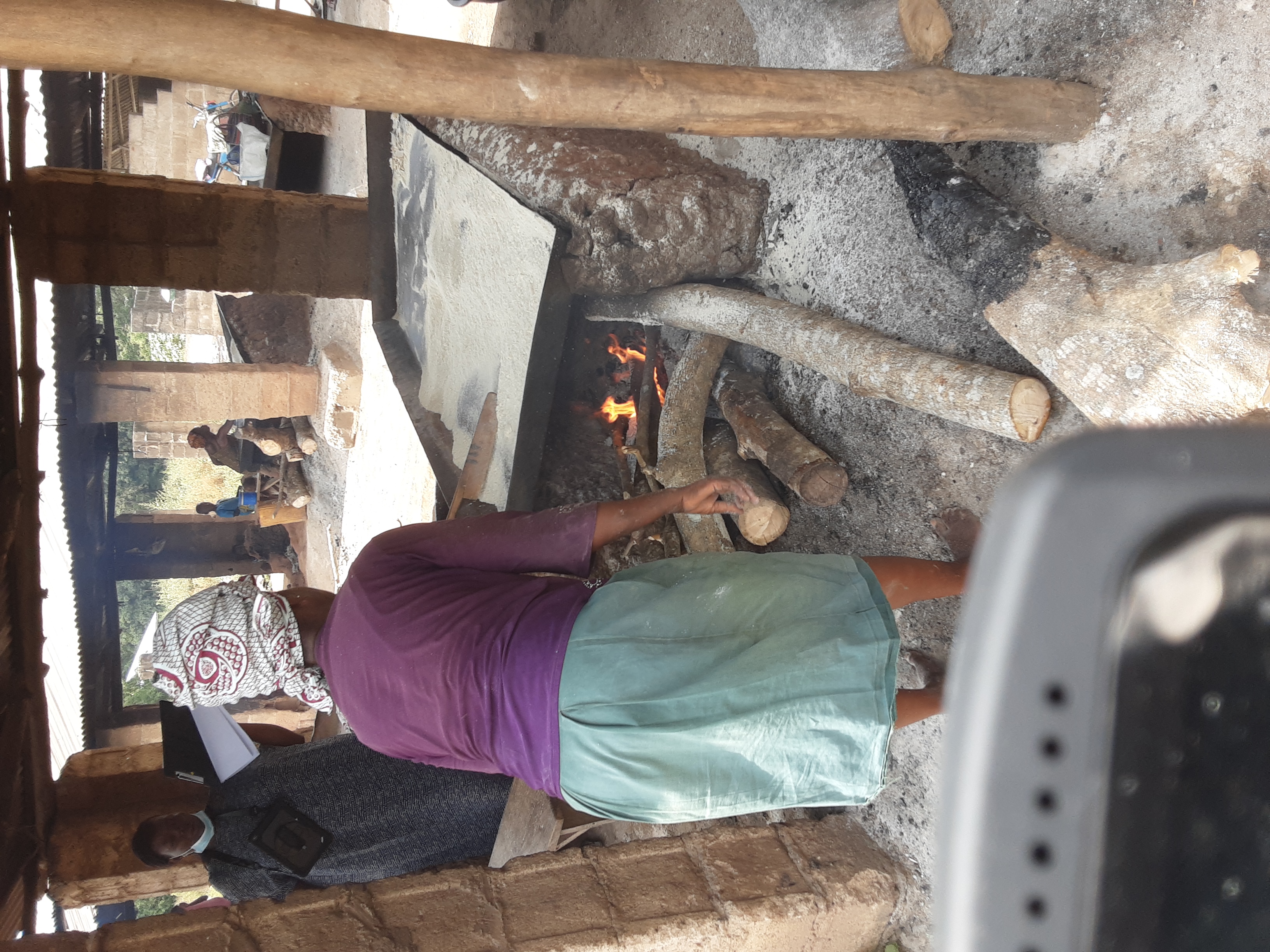 Woman using firewood to fry garri